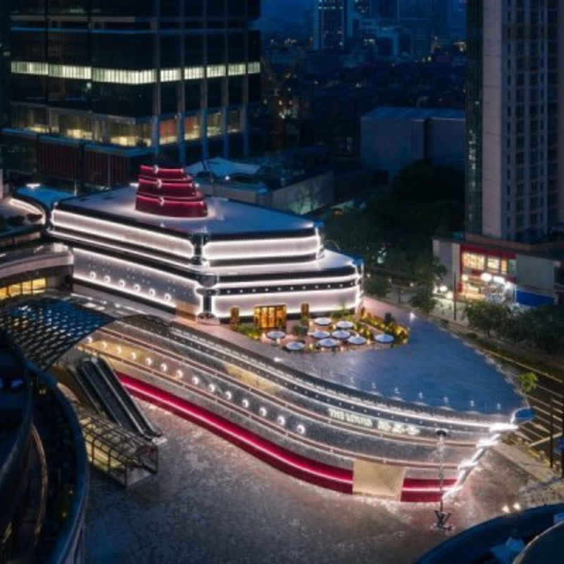 Bâtiment moderne en forme de navire illuminé la nuit.