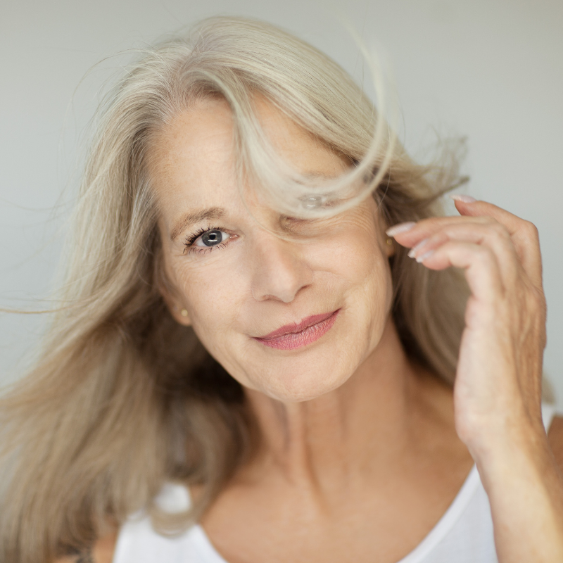 Femme souriante aux cheveux gris avec vent.