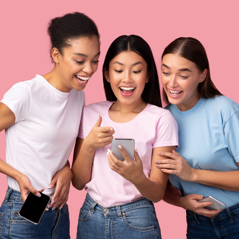 Femmes souriantes regardant un téléphone.