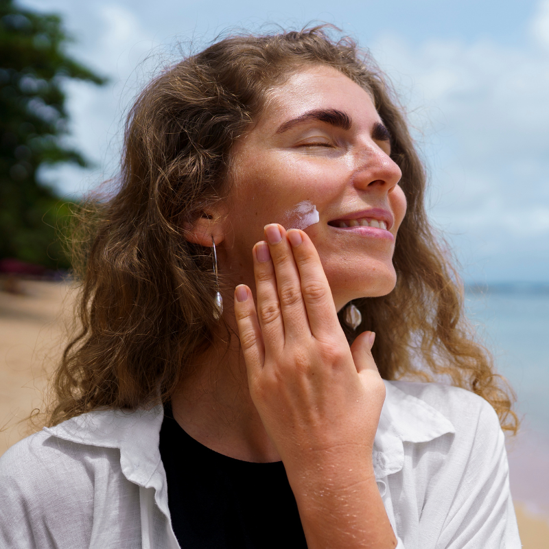 Femme appliquant crème solaire sur la plage.