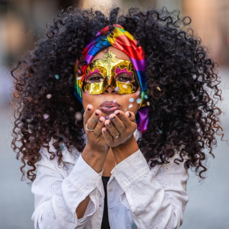 Femme masquée souffle des confettis au carnaval.