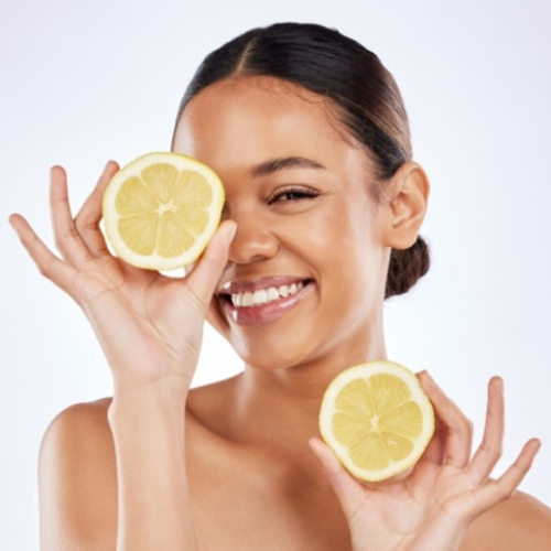 Femme souriante tenant des moitiés de citron