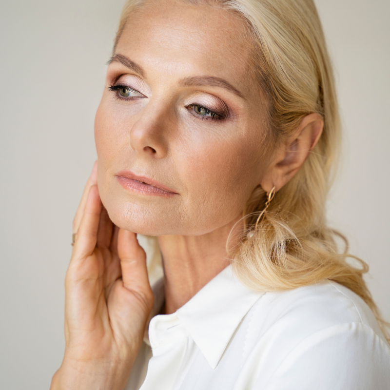 Femme blonde pensive, chemise blanche.