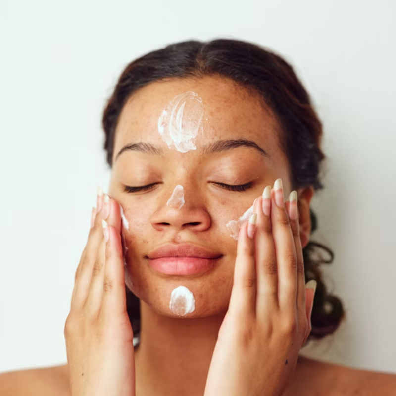 Femme appliquant crème hydratante sur le visage.