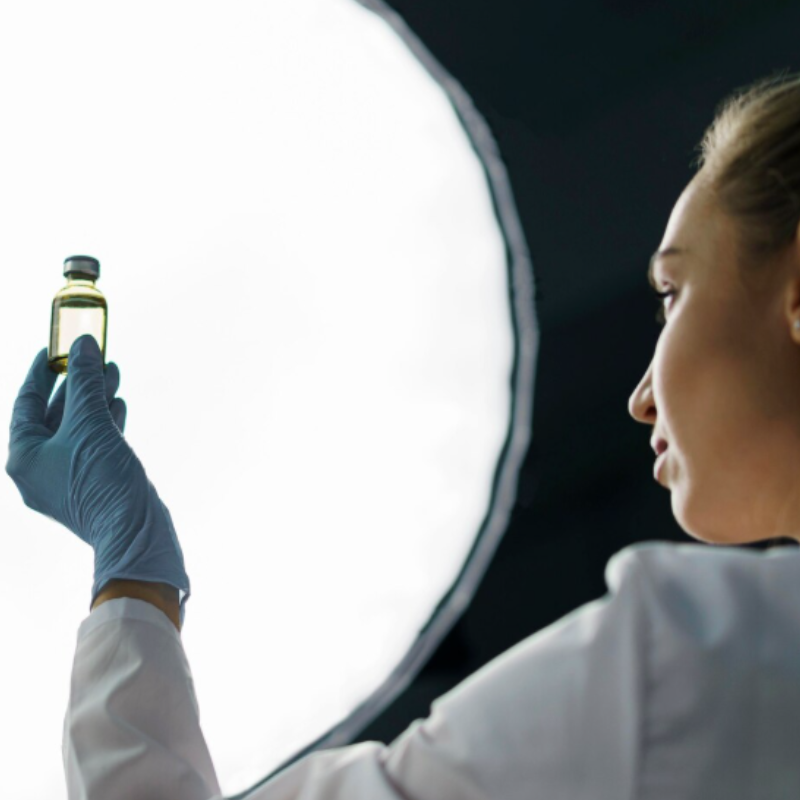 Scientifique examinant un flacon lumineux.