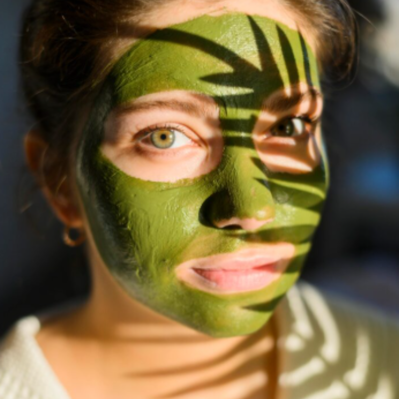 Femme avec masque facial vert et ombres.
