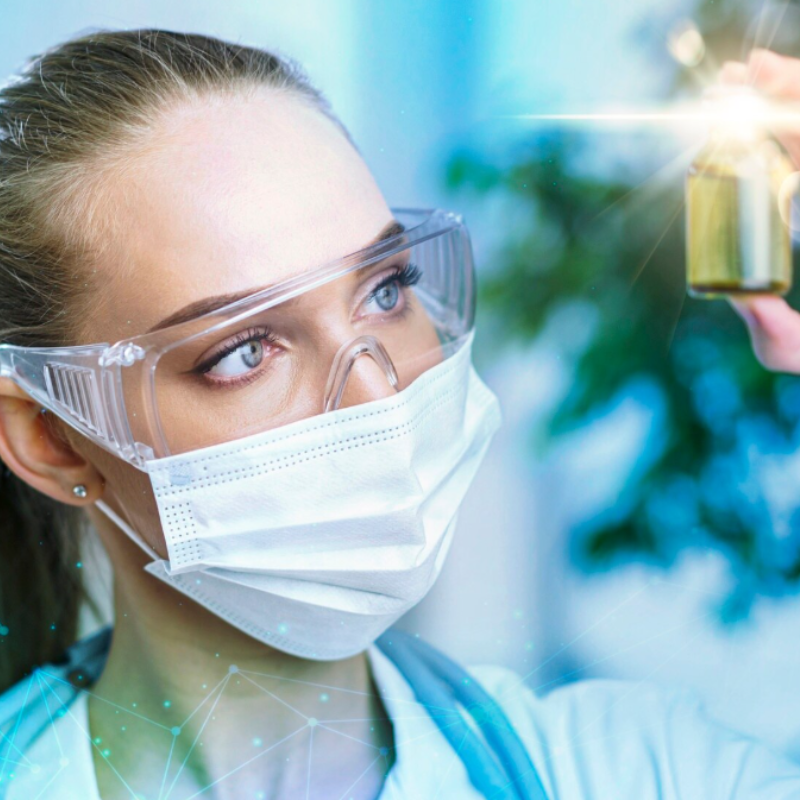 Scientifique en masque examine un flacon.