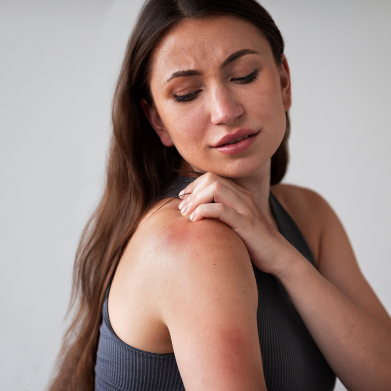 Femme touchant une épaule irritée.