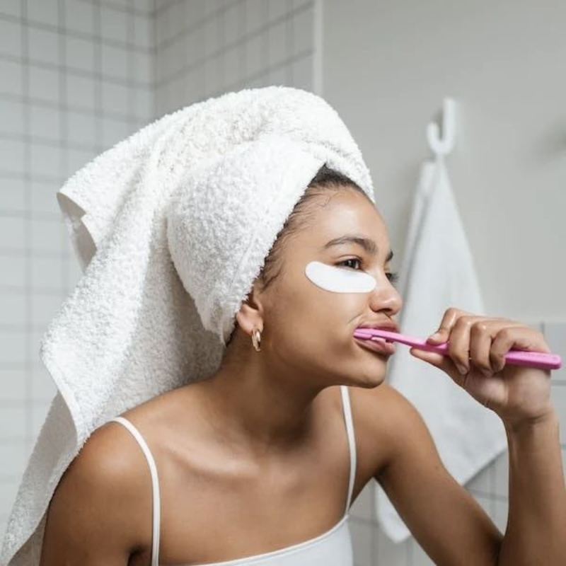 Femme brosse ses dents avec serviette sur la tête.