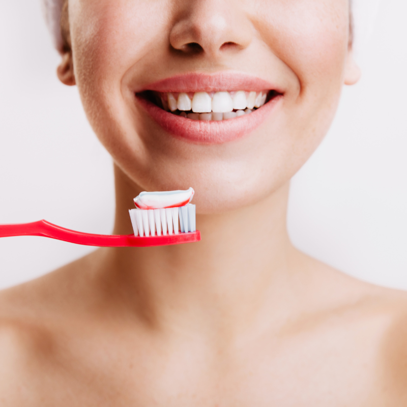 Femme souriante avec brosse à dents rouge