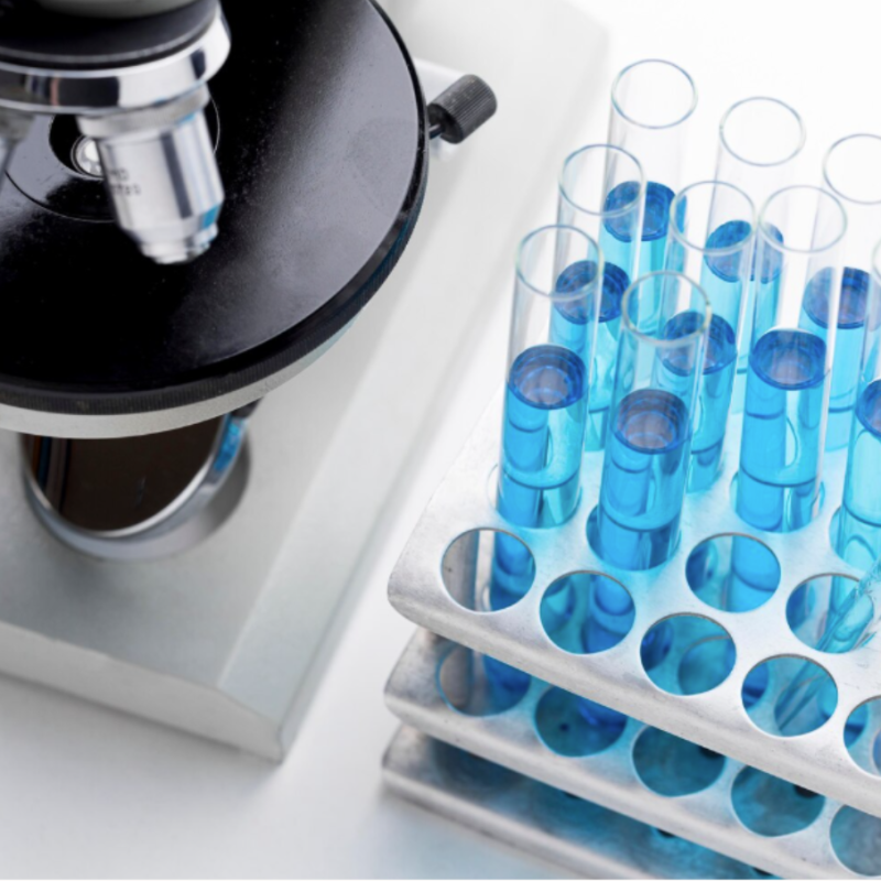 Microscope avec tubes à essai remplis de liquide bleu.