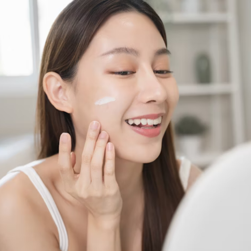 Femme appliquant crème visage devant miroir