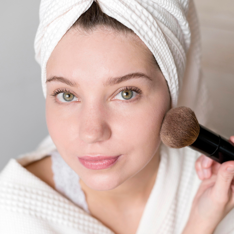 Femme applique maquillage avec pinceau visage.